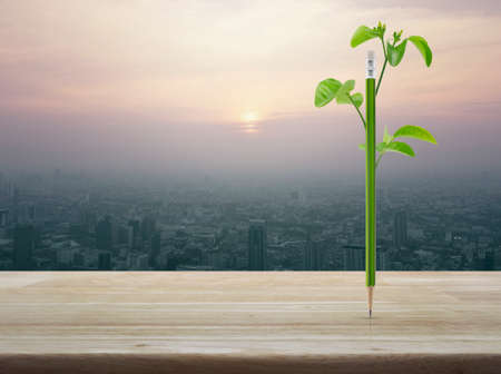 Eco green pencil with leaf on wooden table over city tower at sunset, vintage style, Ecology conceptの写真素材