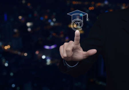 Businessman pressing e-learning icon over blur colorful night light city tower, Study online concept