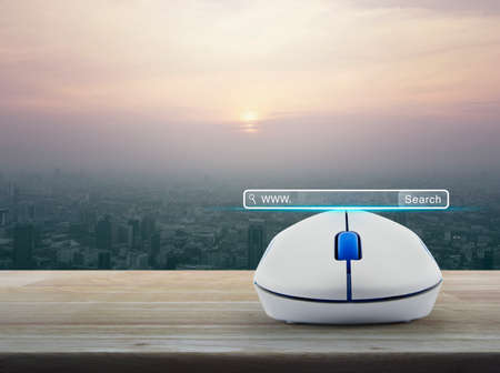 Search www button with wireless computer mouse on wooden table over modern city tower at sunset, vintage style, Searching system and internet conceptの写真素材