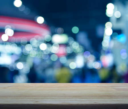 Empty wooden table over defocused light and shadow of shopping mall