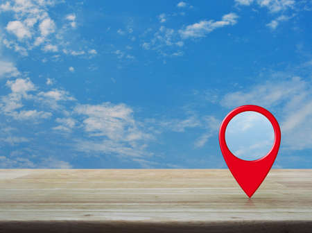 Map pin location button on wooden table over blue sky with white clouds, Map pointer navigation conceptの写真素材
