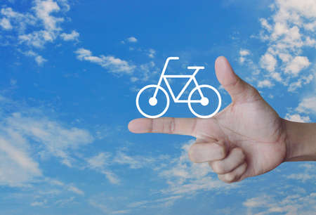 Bicycle flat icon on finger over blue sky, Healthy lifestyle conceptの写真素材