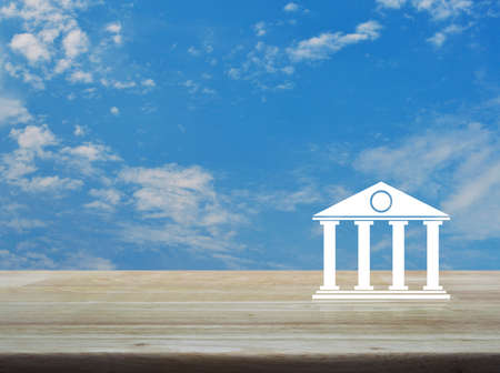 Bank icon on wooden table over blue sky with white clouds, Business banking online conceptの写真素材