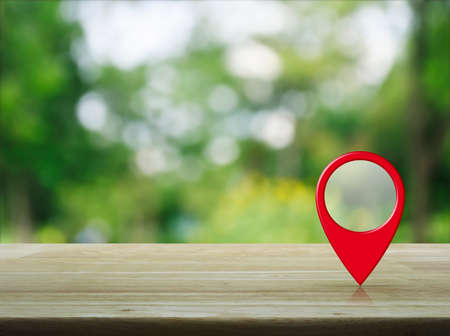 Map pin location button on wooden table over blur green tree in park, Map pointer navigation conceptの写真素材