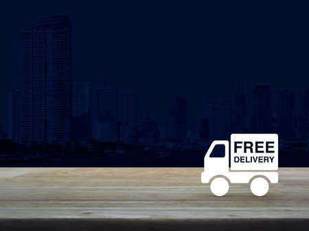 Free delivery truck icon on wooden table over modern office city tower background, Transportation business conceptの写真素材