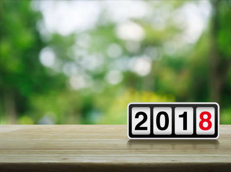 Retro flip clock with 2018 text on wooden table over blur green tree in park, Happy new year conceptの写真素材