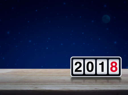 Retro flip clock with 2018 text on wooden table over fantasy night sky and moon, Happy new year...