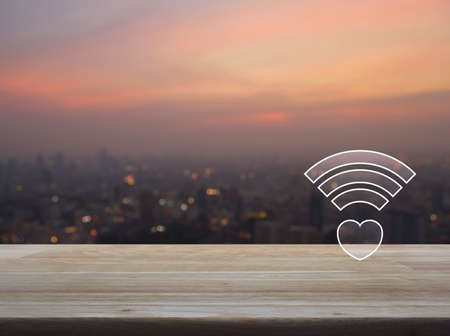 Heart wifi icon on wooden table over blur of cityscape on warm light sundown, Internet online love connection, Valentines day conceptの写真素材