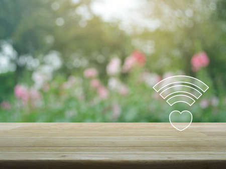 Heart wifi icon on wooden table over blur pink flower and tree, Internet online love connection, Valentines day conceptの写真素材