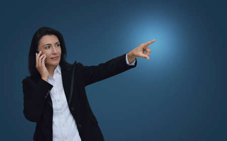 Caucasian business woman talking on her cell phone and pointing or touching touchscreen over...