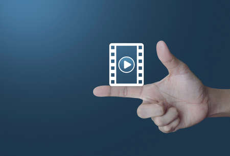 Play button with movie icon on finger over light gradient blue background, Cinema online conceptの写真素材