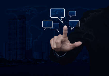 Businessman point to social chat sign and speech bubbles over world map and modern city tower,...