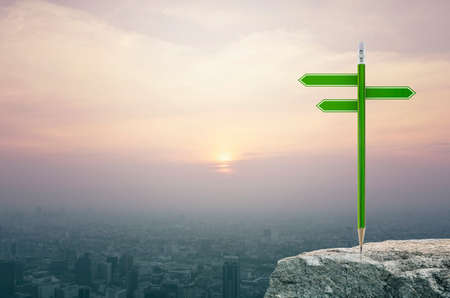 Green pencil with blank sign plate on rock over aerial view of cityscape at sunset, vintage style, Business presentation conceptの写真素材