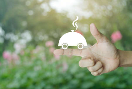 Restaurant cloche flat icon on finger over blur pink flower and tree, Food delivery conceptの写真素材