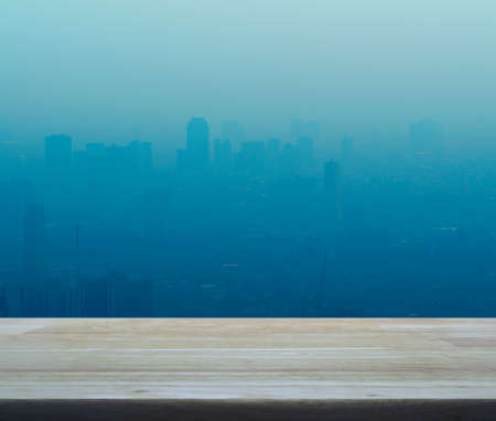 Empty wooden table in front of big city in the fog, for your product display montage