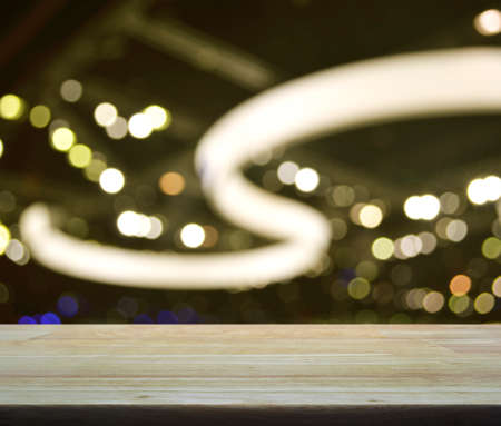 Empty wooden table over defocused light and shadow of shopping mall, Abstract background