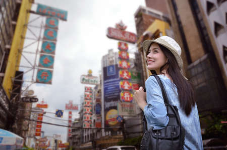 Young asian woman traveler with a backpack on her shoulder and travel hat walking on footpath over China town, Bangkok, Thailand, Travel holiday relaxation conceptのeditorial素材