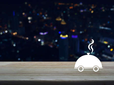 Restaurant cloche flat icon on wooden table over blur colourful night light city tower background,...