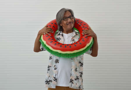 Happy senior traveler asian man wearing glasses, summer shirt and brown shorts in watermelon...