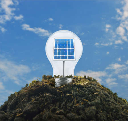 Light bulb with solar cell inside on pile of soil over blue sky with white clouds, Ecological power...