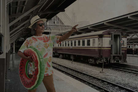 Happy elderly traveler asian man wearing summer t-shirt, straw hat and sunglasses, pointing finger...