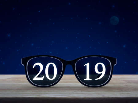 2019 white text with black eye glasses on wooden table over fantasy night sky and moon, Business vision happy new year 2019 conceptの写真素材