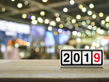 Retro flip clock with 2019 text on wooden table over blur light and shadow of shopping mall, Happy new year cover conceptの写真素材