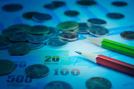 Red and green pencils with thailand coins amd banknotes on growth graph, Business planning concept