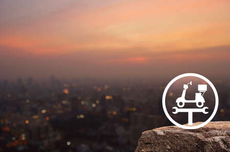 Service fix motorcycle with wrench tool flat icon on rock over blur of cityscape on warm light sundown, Business repair motorbike conceptの写真素材