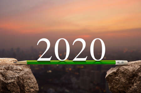2020 white text with green pencil on rock mountain over blur of cityscape on warm light sundown, Business success strategy plan concept, Happy new year 2020 calendar coverの写真素材