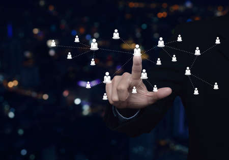 Hand click businessman flat icon with connection line over blur colorful night light modern city tower and skyscraper, Business communication conceptの写真素材