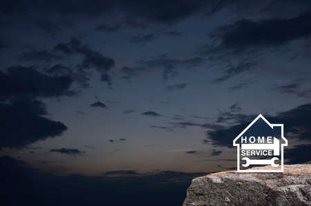 Hammer and wrench with house flat icon on rock mountain over sunset sky, Business home service conceptの写真素材