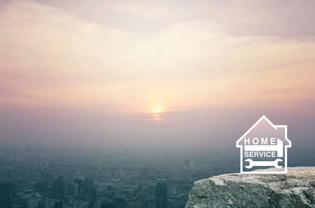 Hammer and wrench with house flat icon on rock mountain over aerial view of cityscape at sunset, vintage style, Business home service conceptの写真素材
