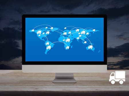 Delivery truck flat icon with connection line and world map on modern computer monitor screen on wooden table over sunset sky, Business transportation online conceptの写真素材