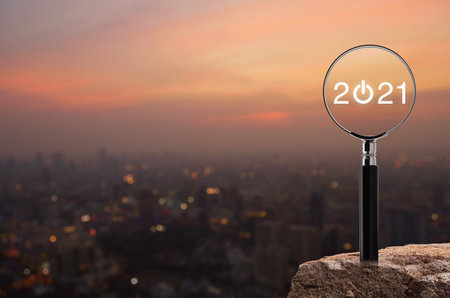 2021 start up flat icon with magnifying glass on rock mountain over blur of cityscape on warm light...