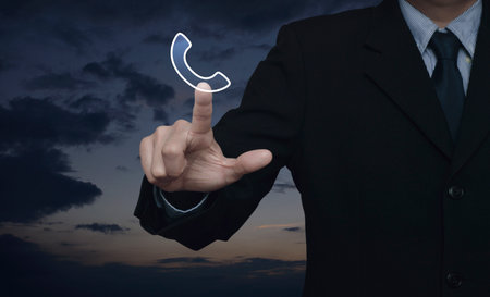 Businessman pressing telephone flat icon over sunset sky, Business contact us, Customer service and...