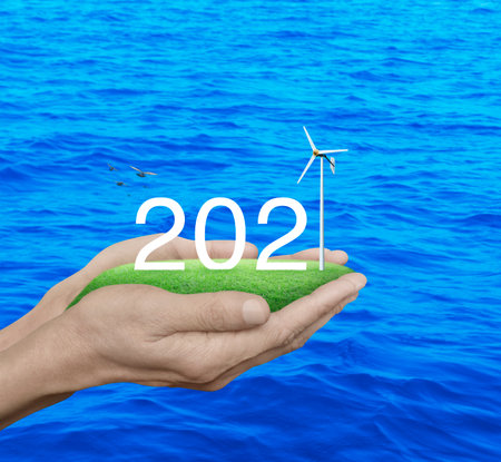 2021 white text with wind turbine on green grass field in man hands over blue sea with birds, Happy...