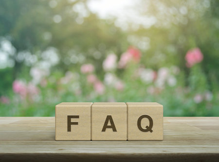 FAQ word on block cubes on wooden table over blur pink flower and tree in garden, Frequently asked questions, Business customer service and support conceptの写真素材