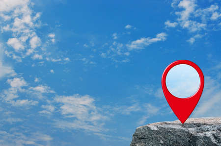 Map pin location button on rock mountain over blue sky with white clouds, Map pointer navigation conceptの写真素材