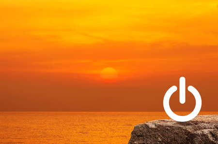 Power button icon on rock mountain over sunset sky and sea, Start up business concept