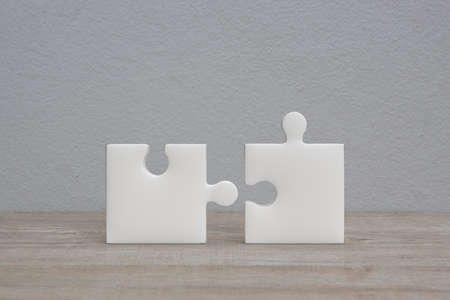Connecting couple jigsaw puzzle on wooden table over white wall background, Business teamwork or partnership conceptの写真素材