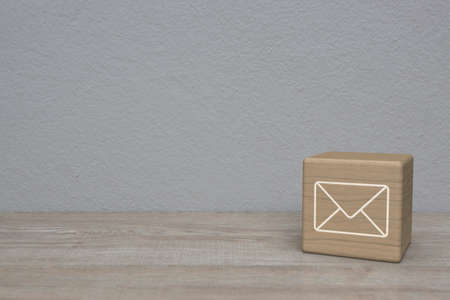 Mail flat icon on block cube on wooden table over white wall background, Business customer service...