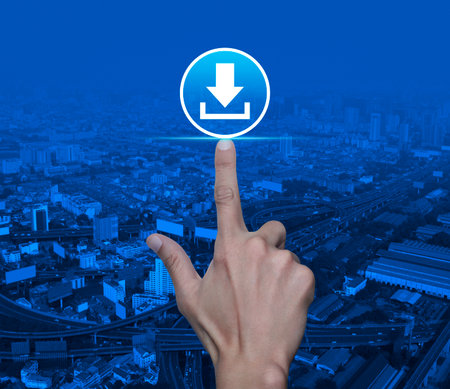 Hand pressing download flat icon over modern city tower, street, expressway and skyscraper, Technology internet online conceptの写真素材