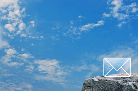 Mail flat icon on rock mountain over blue sky with white clouds, Business customer service and support online conceptの写真素材