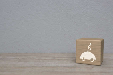 Restaurant cloche flat icon on block cube on wooden table over white wall background, Business food delivery online conceptの写真素材