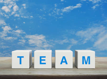 TEAM letter on white block cubes on wooden table over blue sky with white clouds, Business teamwork communication conceptの写真素材