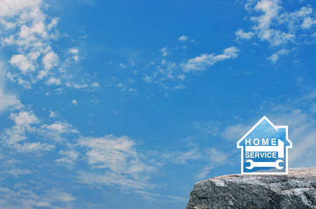 Hammer and wrench with house flat icon on rock mountain over blue sky with white clouds, Business home service conceptの写真素材