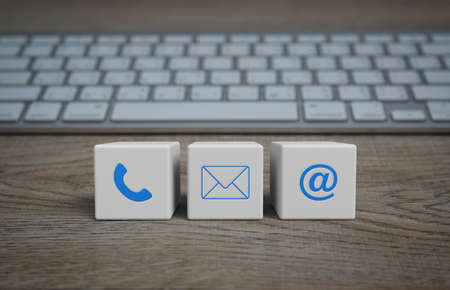 Telephone, mail, email address icon on white block cubes on wooden table with computer keyboard, Business customer service and support online conceptの写真素材
