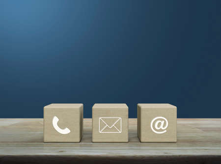 Telephone, mail, email address icon on wood block cubes on wooden table over light blue gradient background, Business customer service and support online conceptの写真素材