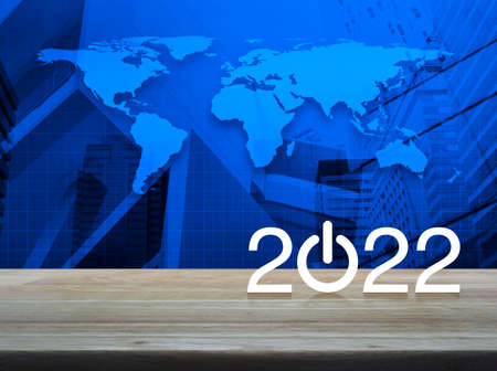 2022 start up business flat icon on wooden table over world map, modern city tower and skyscraper, Happy new year 2022 cover conceptの写真素材